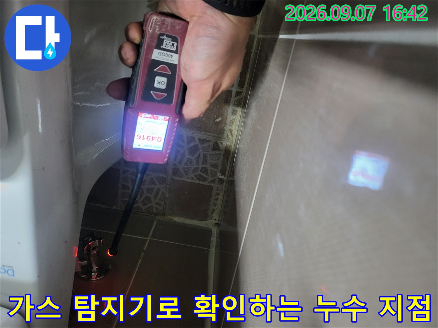 화장실 벽면 배관 근처에서-가스 탐지기를 사용하여-누수 수치를 측정하고 있습니다