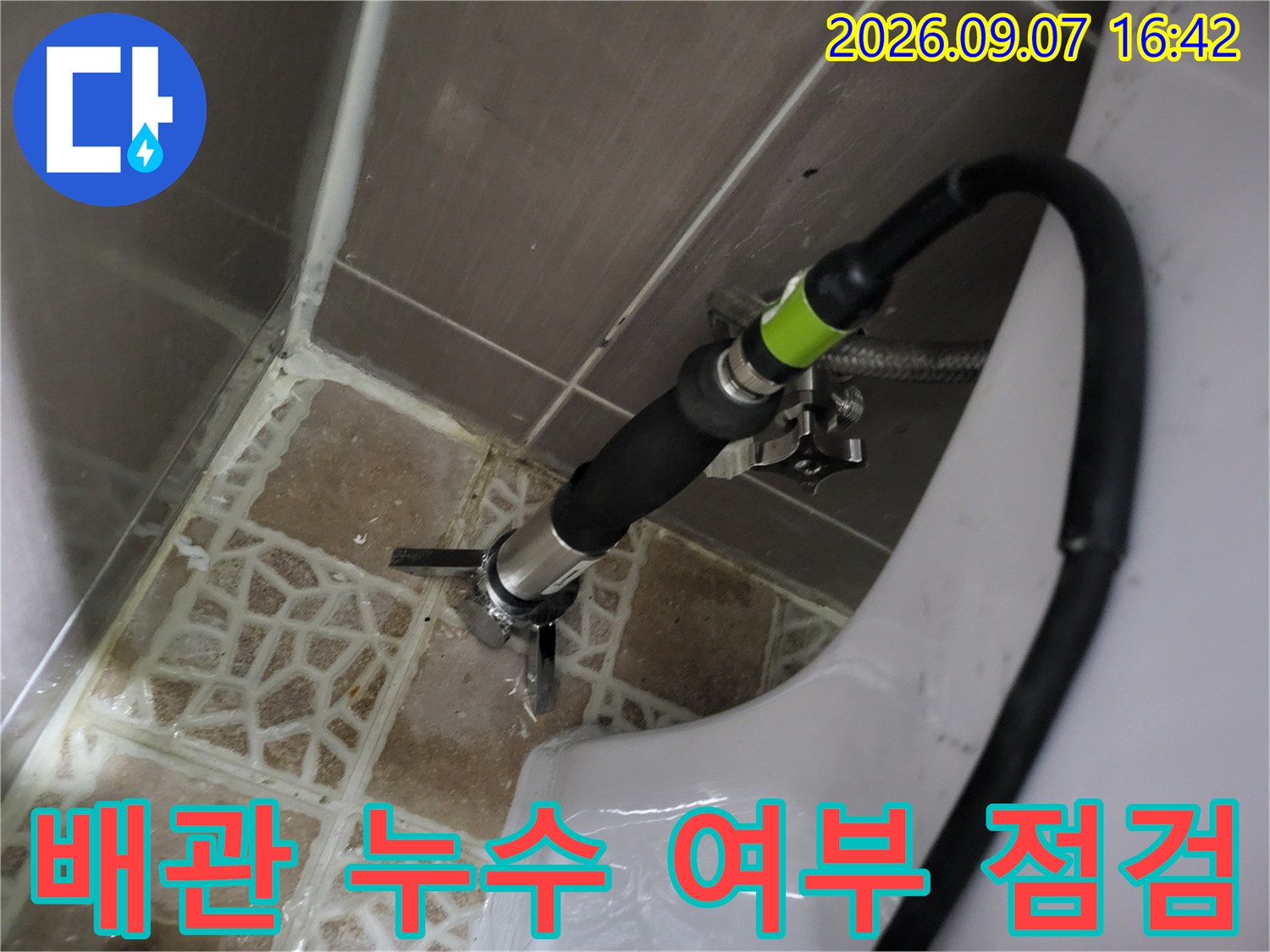 화장실 변기 뒤쪽 배관 연결 부위에 장비를 설치하여 점검하는 모습