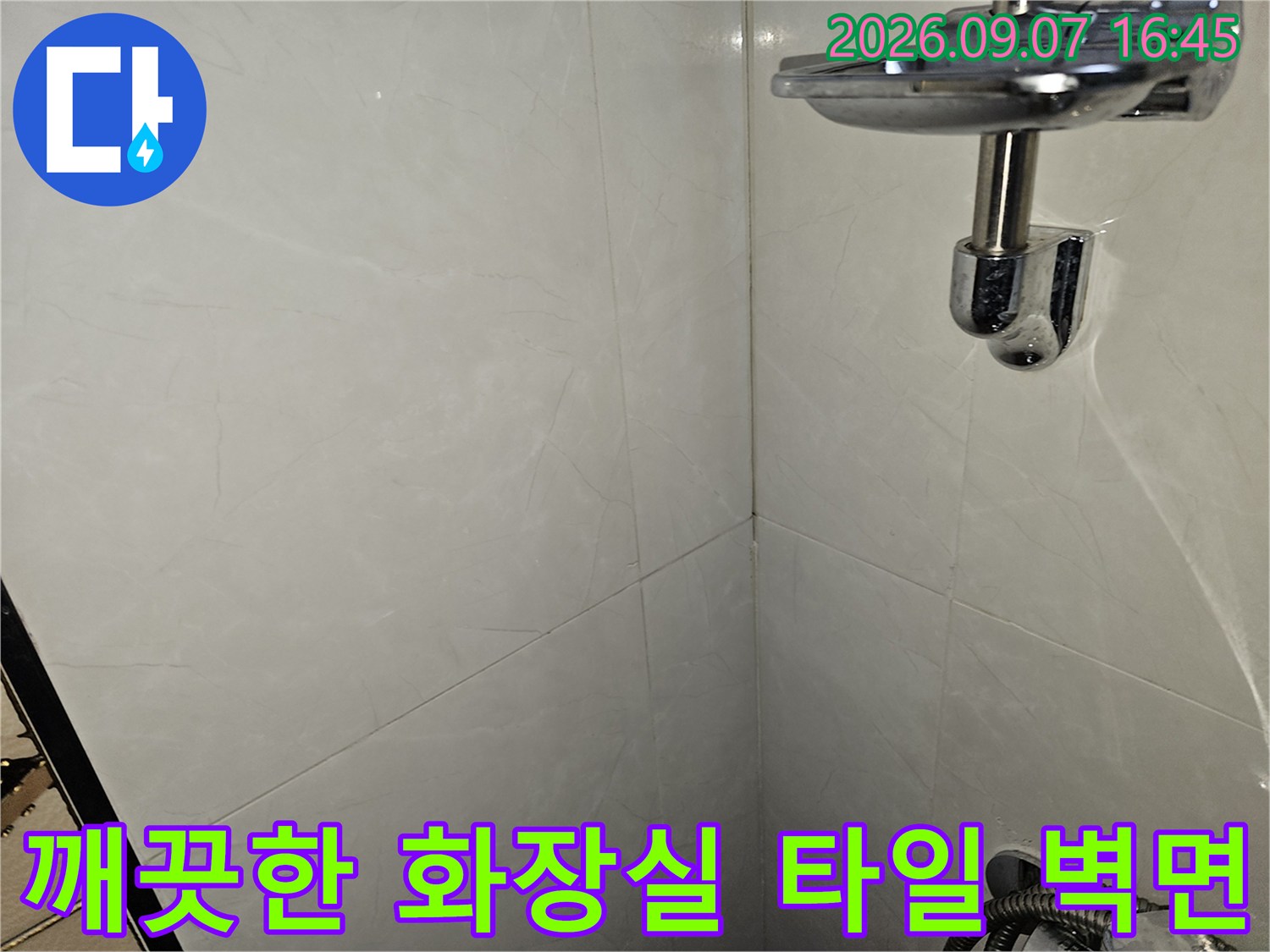 대리석 패턴의 흰색 타일과 반짝이는 샤워기 수전 부위