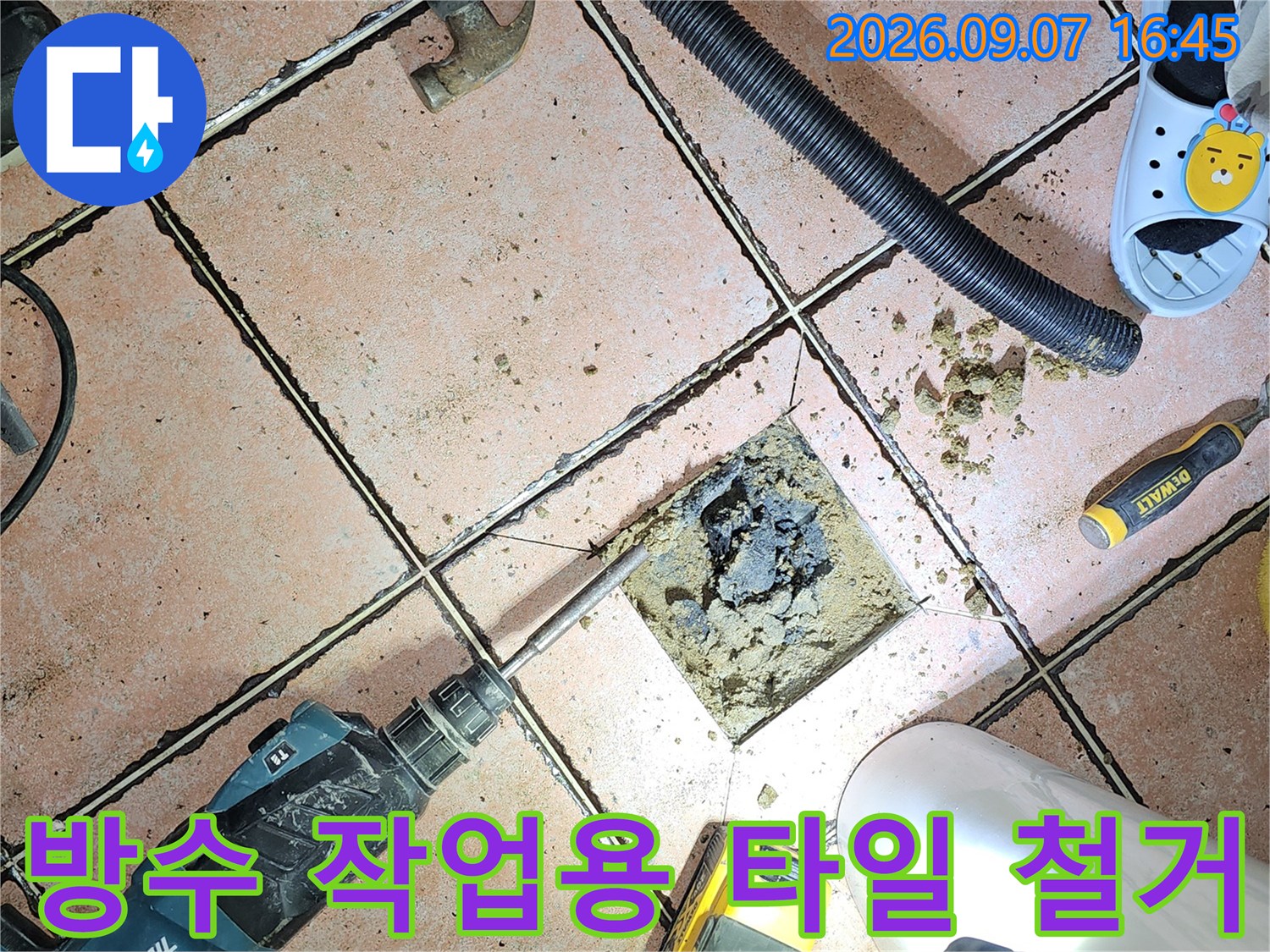 욕실 배수구 유가 주변의 손상된 방수층을 드러내기 위해 타일을 제거한 모습입니다.