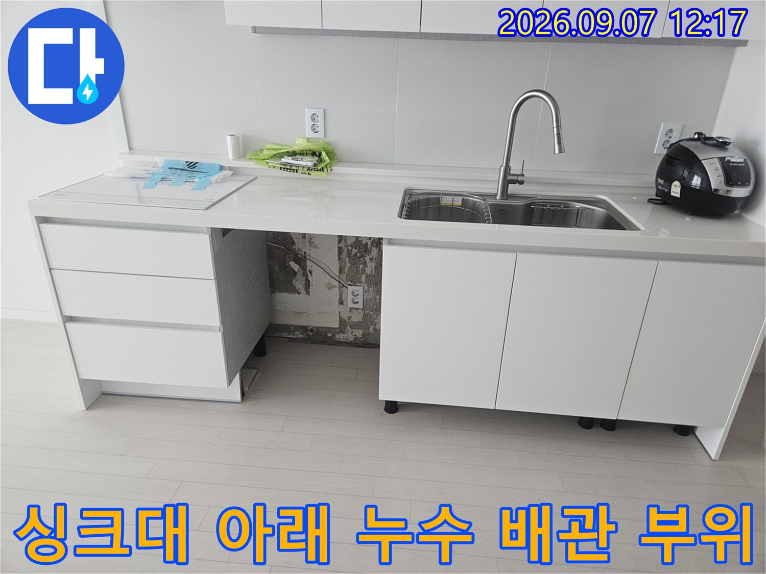 싱크대 하부의 훼손된 호스와 연결 부위를 근접 촬영한 사진입니다.