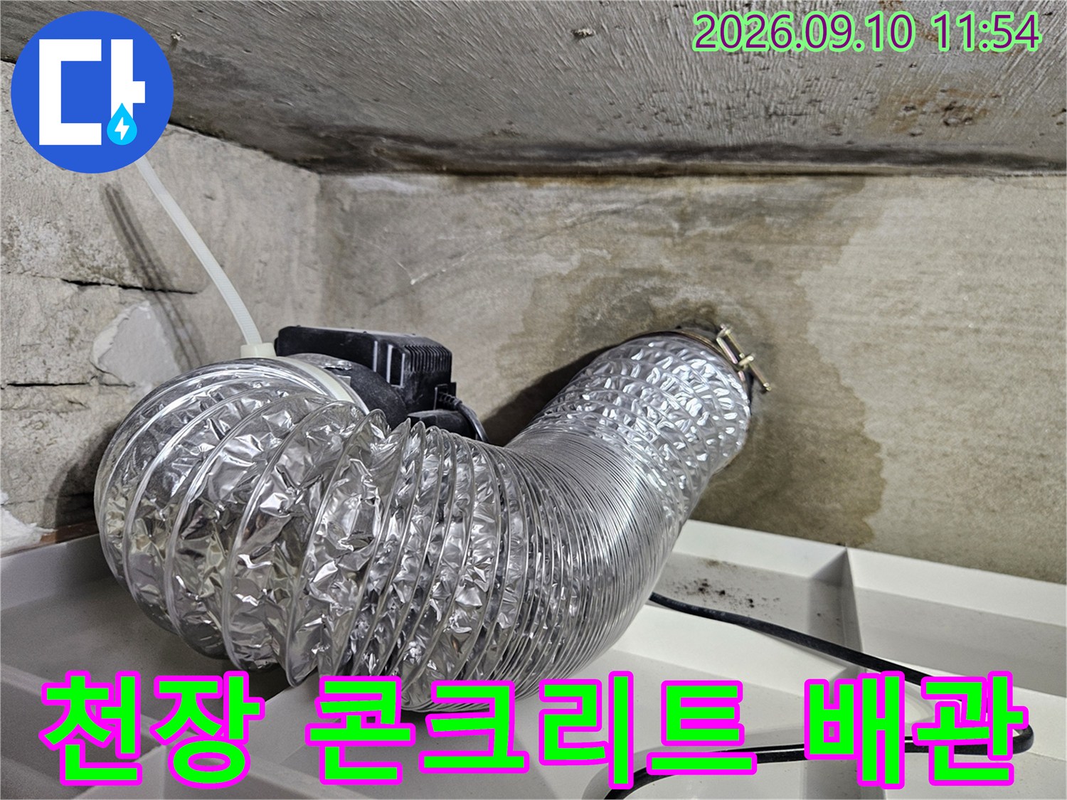 콘크리트 천장을 지나는 은박 자바라 배관의 근접 사진