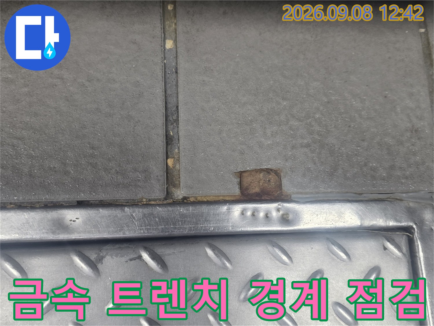 식당 주방의 금속 트렌치 테두리와 타일 접합부 오염 상태를 보여주는 사진입니다.