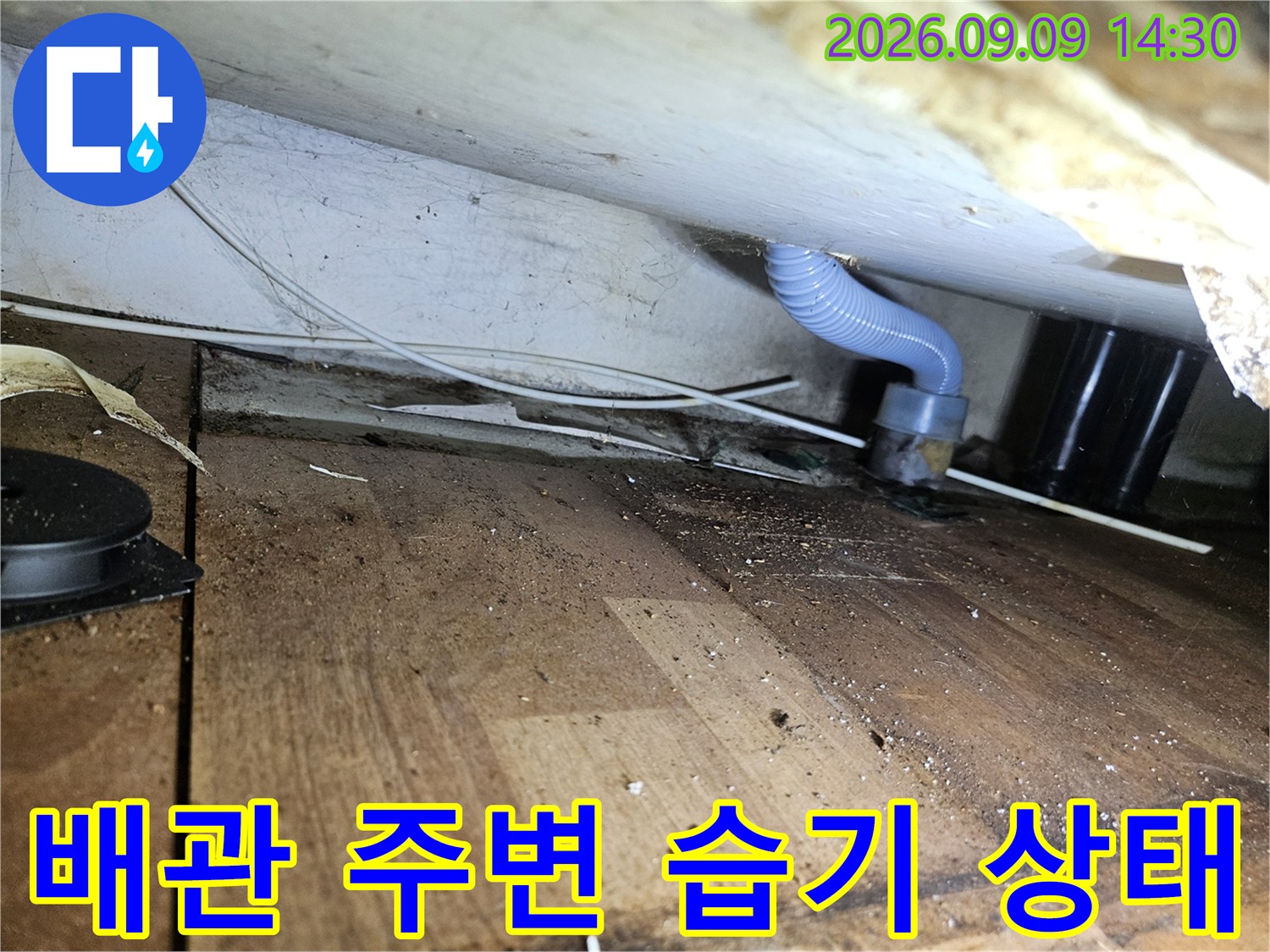천장 하부 배관 연결 부위와 - 나무 바닥면의 접합부를 근접 촬영하였습니다.