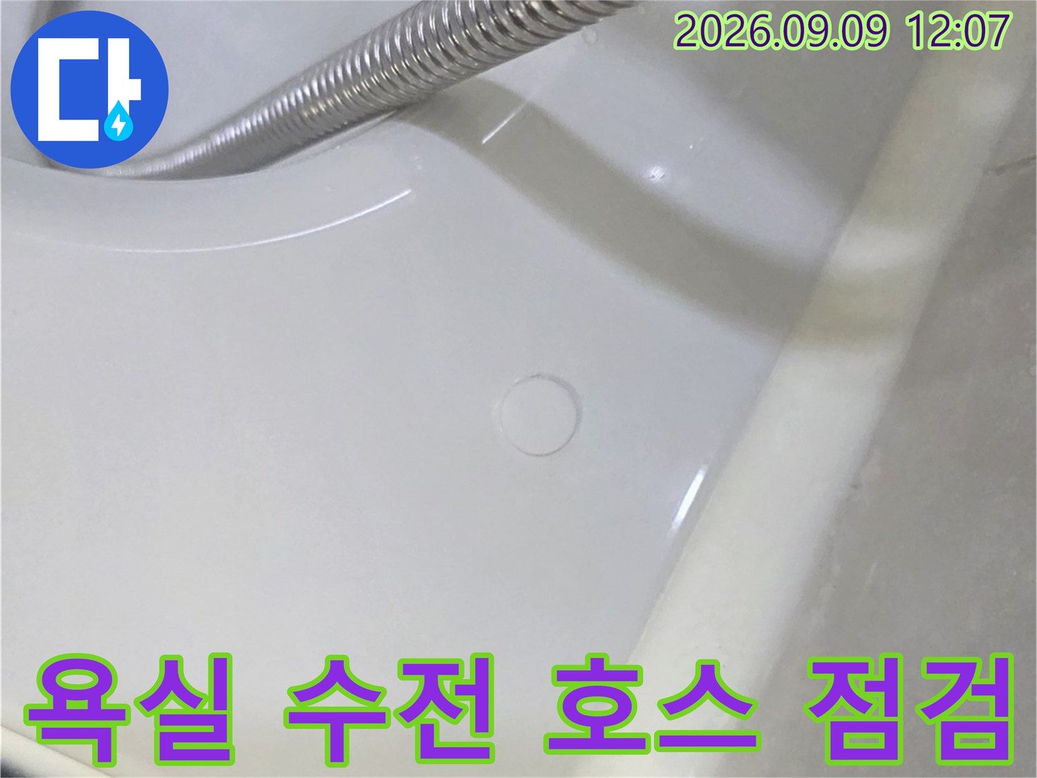 샤워기 줄과 하얀색 욕실 벽면이 촬영된 사진입니다.