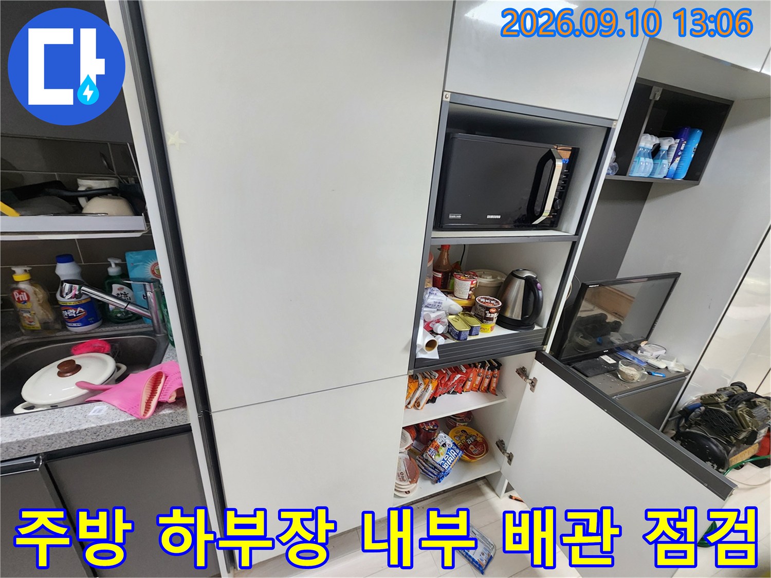 주방-싱크대-하부의-선반과-전자레인지-및-수납된-물건들-배관-점검