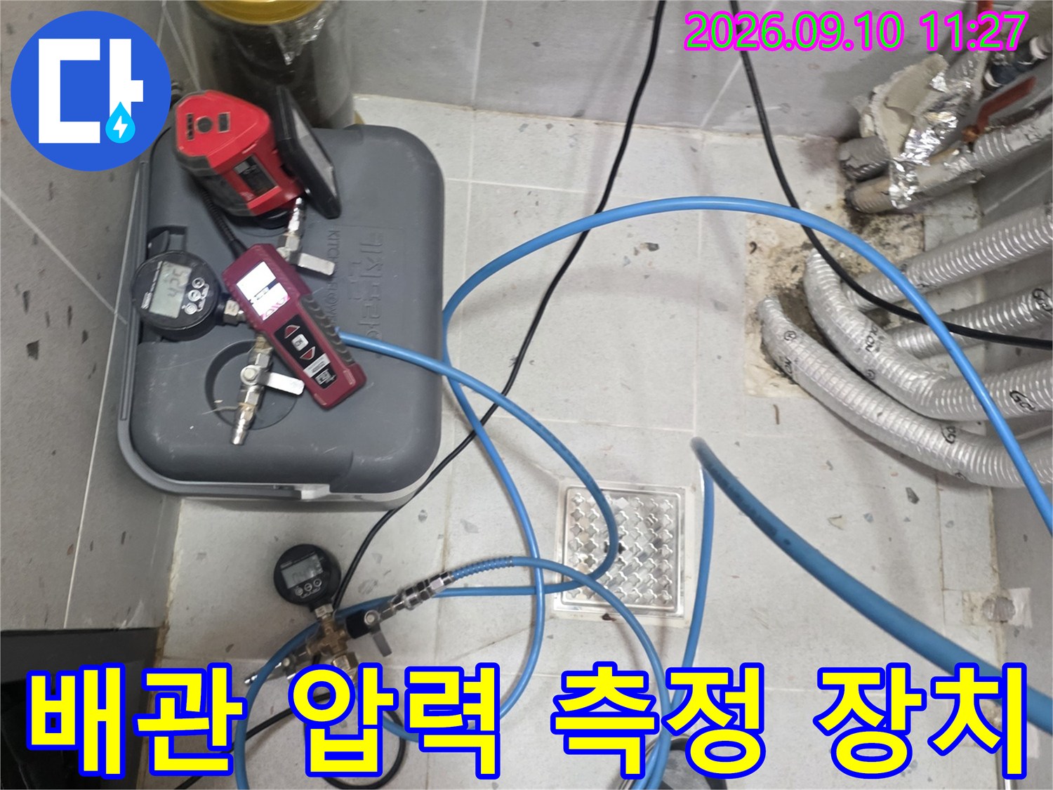 누수 탐지를 위해 배관에 연결된 파란색 호스와 게이지 장비