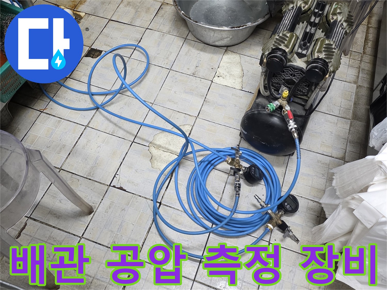 바닥에 펼쳐진 파란색 에어 호스와 압력 조절 밸브 장치