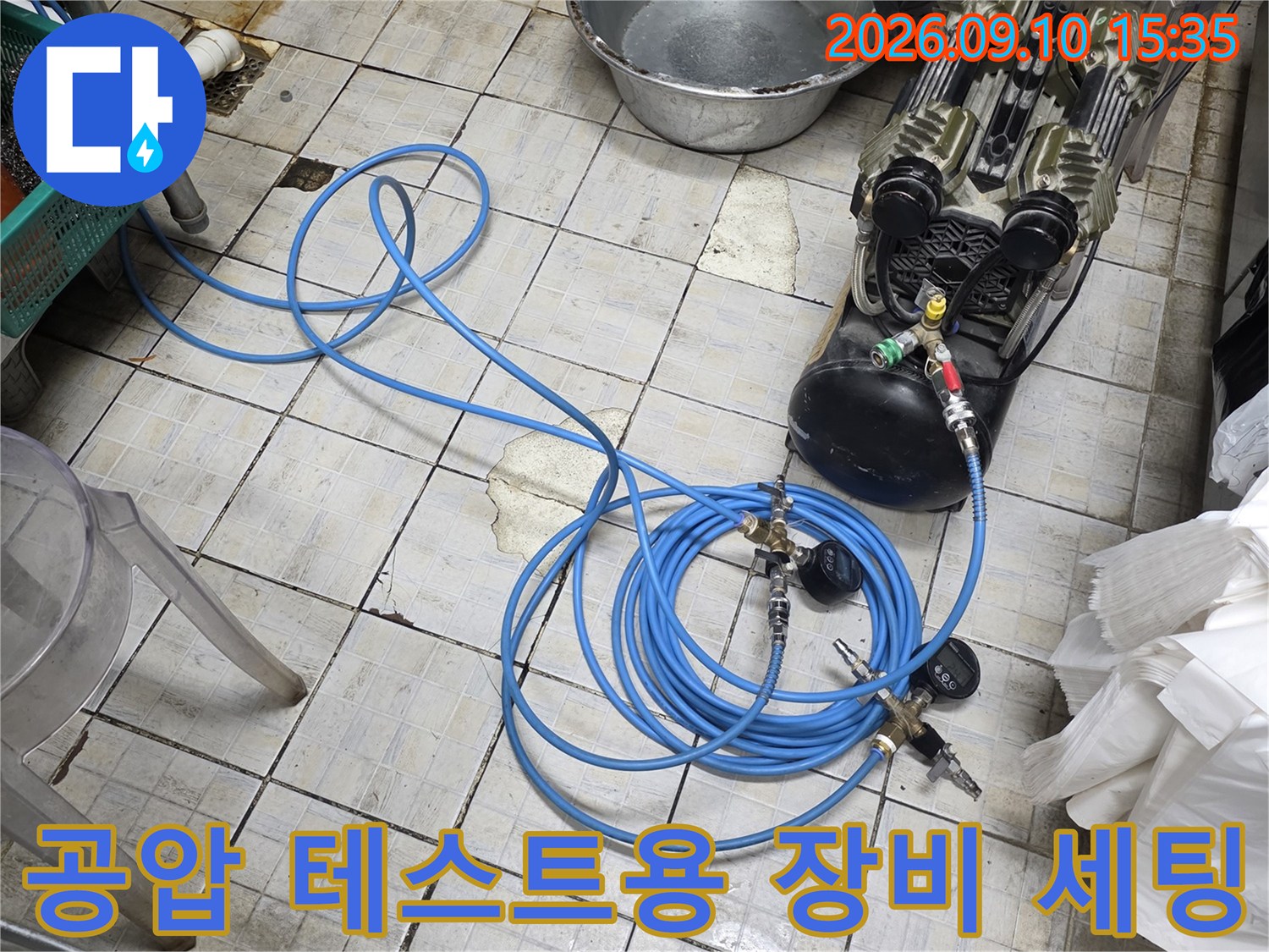 주방 타일 바닥에 설치된 공기 압축기와 연결 호스