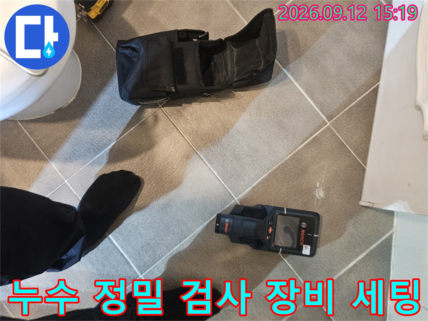 화장실 타일 바닥에 놓인 열화상 카메라와 작업용 가방