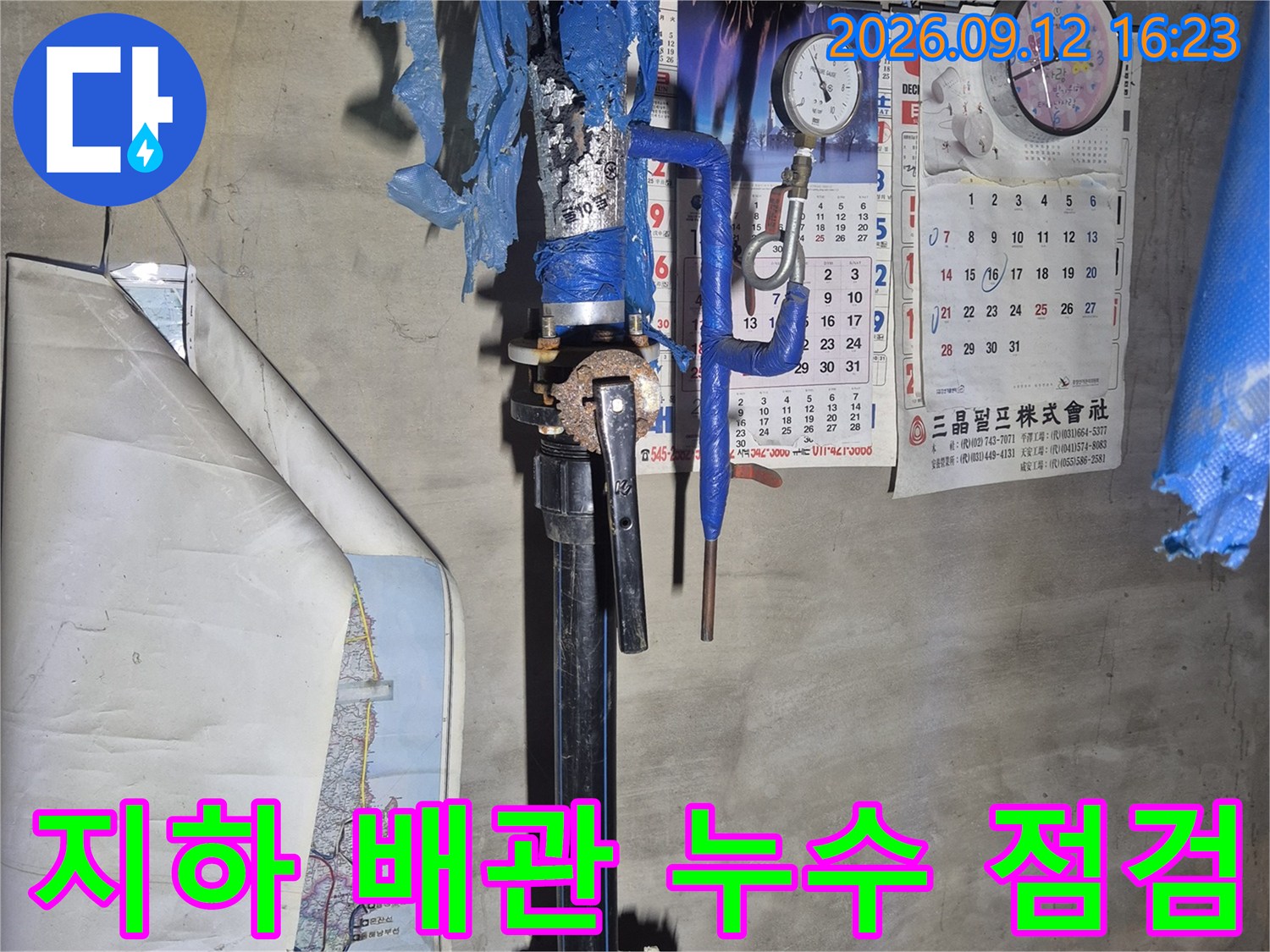 천안 서북구 아파트 지하 공간의 파란색 보온재로 감싸진 급수 배관과 계량기 모습입니다.