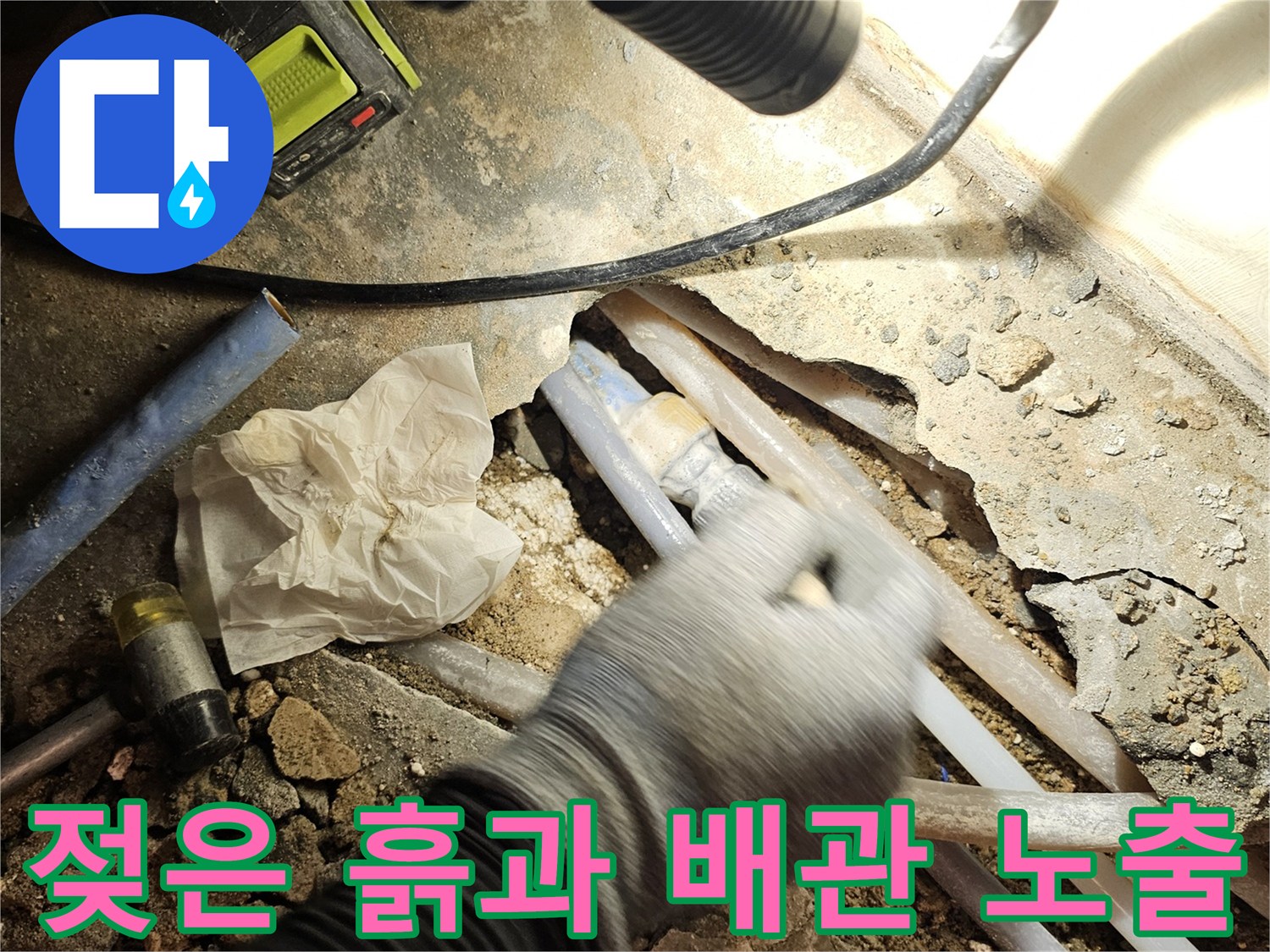 누수로 인해 젖어 있는 흙과 드러난 배관의 연결 부위 사진입니다.