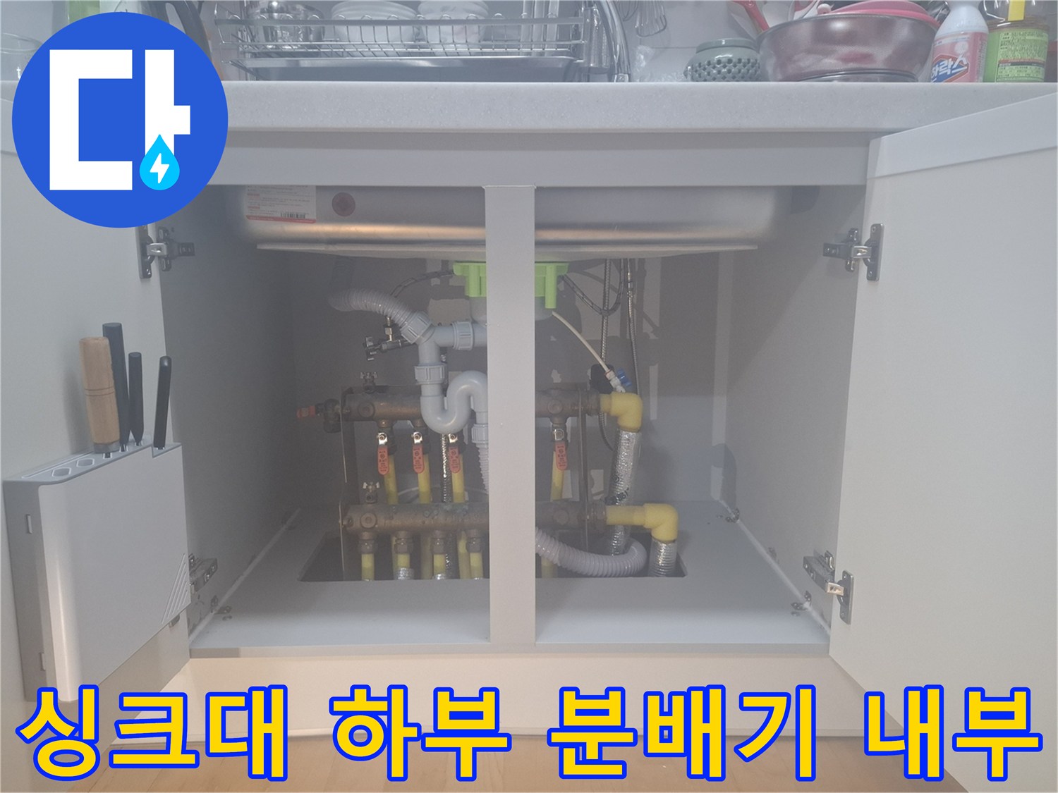 싱크대 하부장에 노출된 난방 분배기와 각종 배관 연결 부위