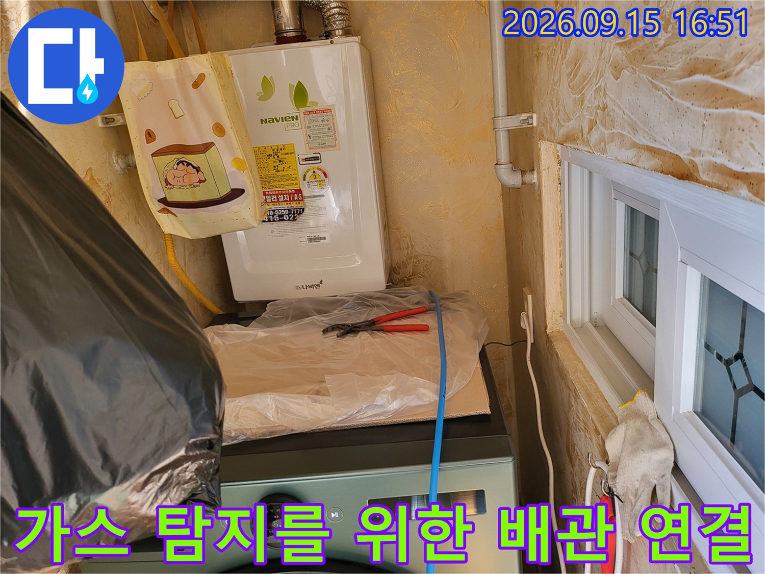 보일러 하단 배관에 가스 탐지용 호스를 연결하여 점검하고 있습니다.