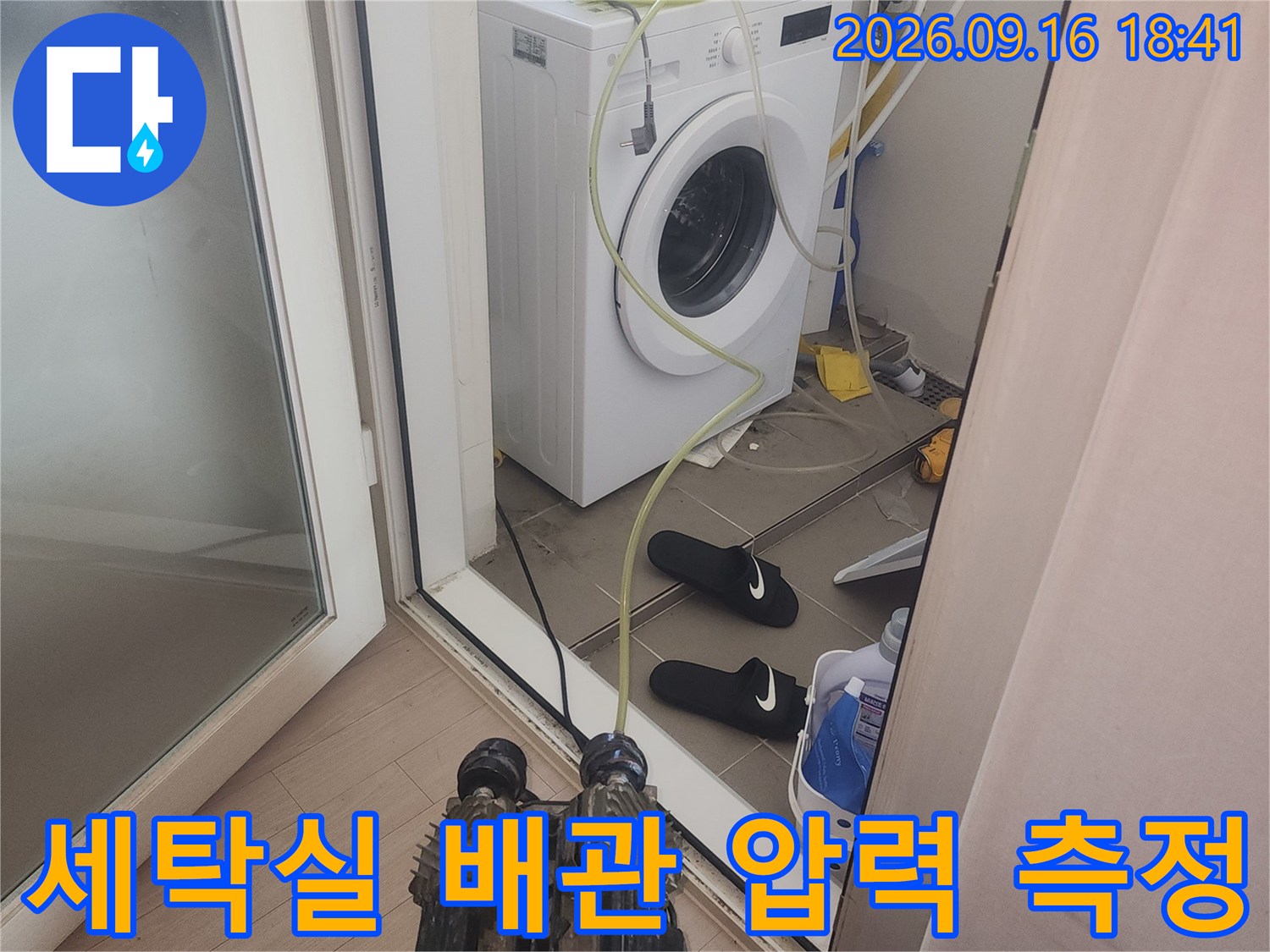세탁기 옆 배관에 연결된 공압 검사 장치와 호스 모습입니다.