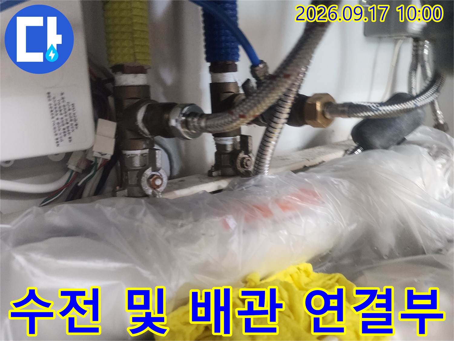 싱크대 아래쪽 수전 연결 부위와 주변 배관들을 상세하게 촬영한 사진입니다.