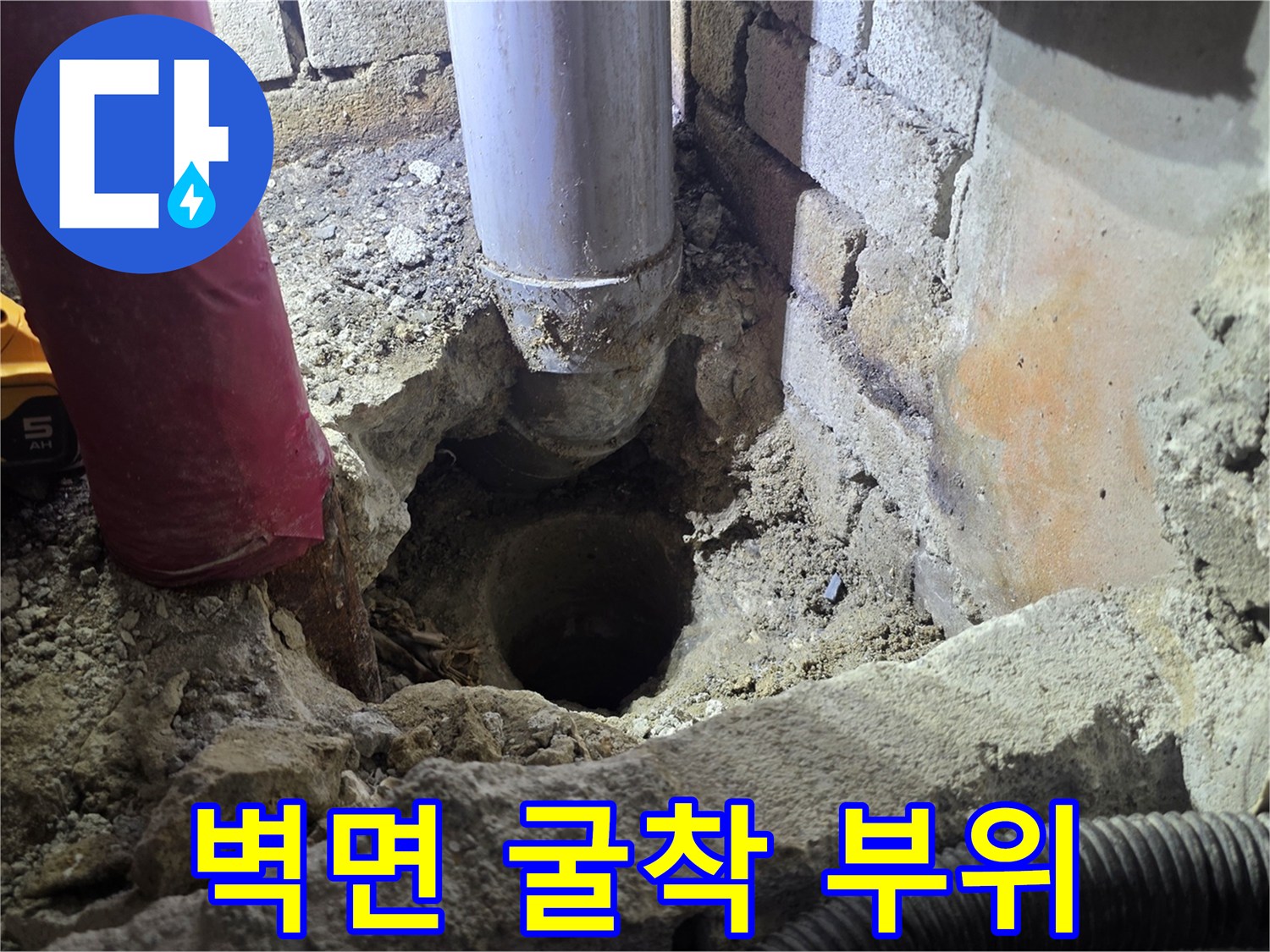공사 중인 벽면 내부의 노출된 하수 배관과 작업 장비