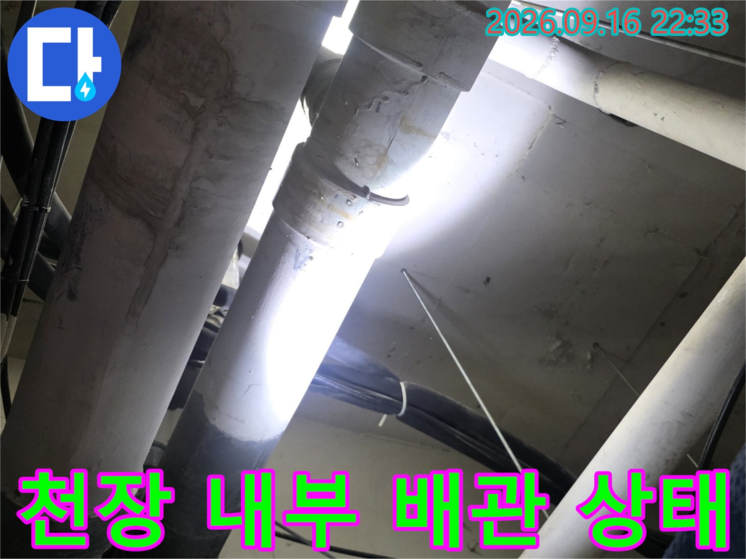 아파트 천장 점검구 내부의 흰색 배관과 전선 뭉치 모습